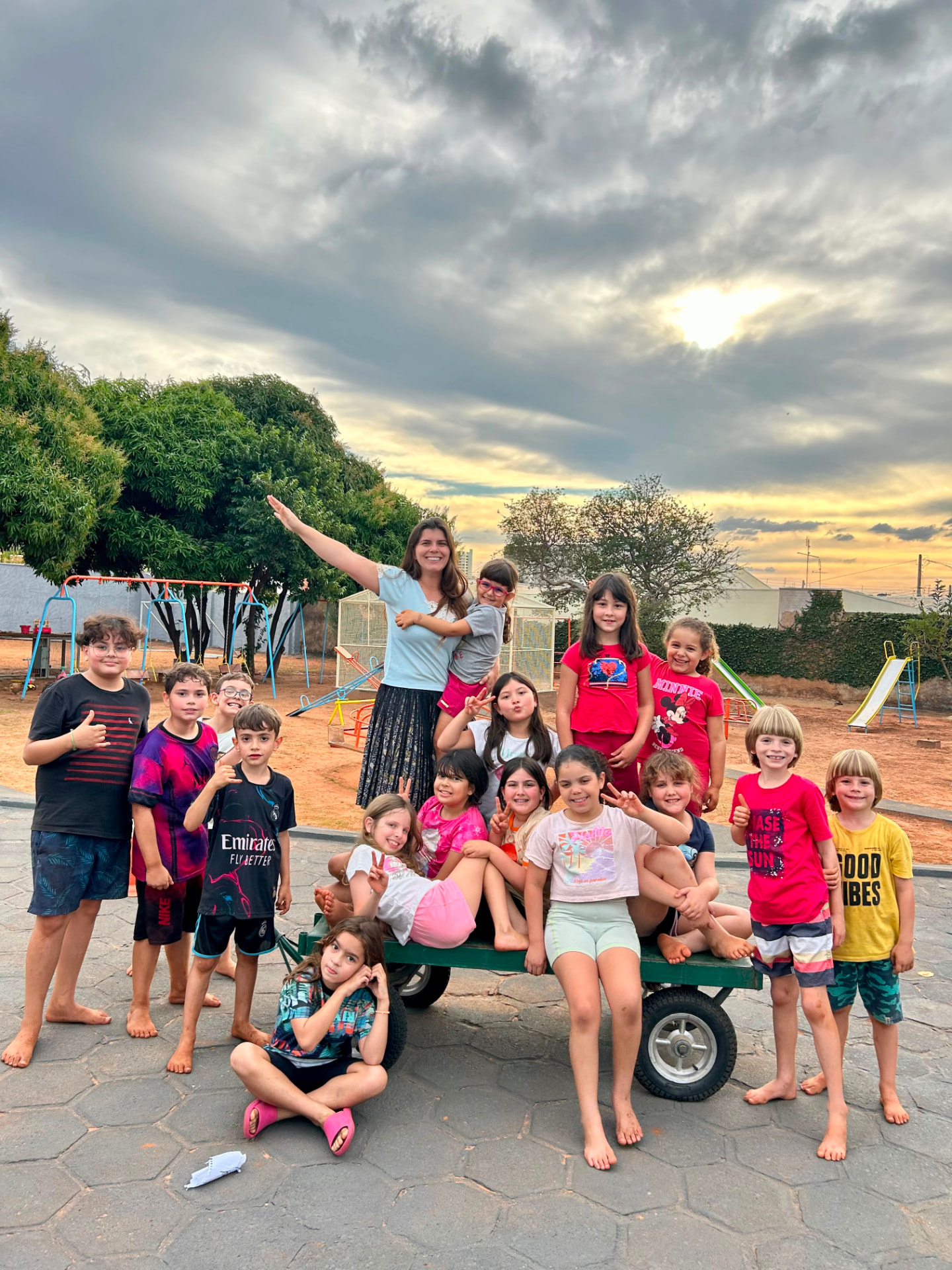 Grupo de crianças e educadora reunidos no pátio da Talsce no fim da tarde.